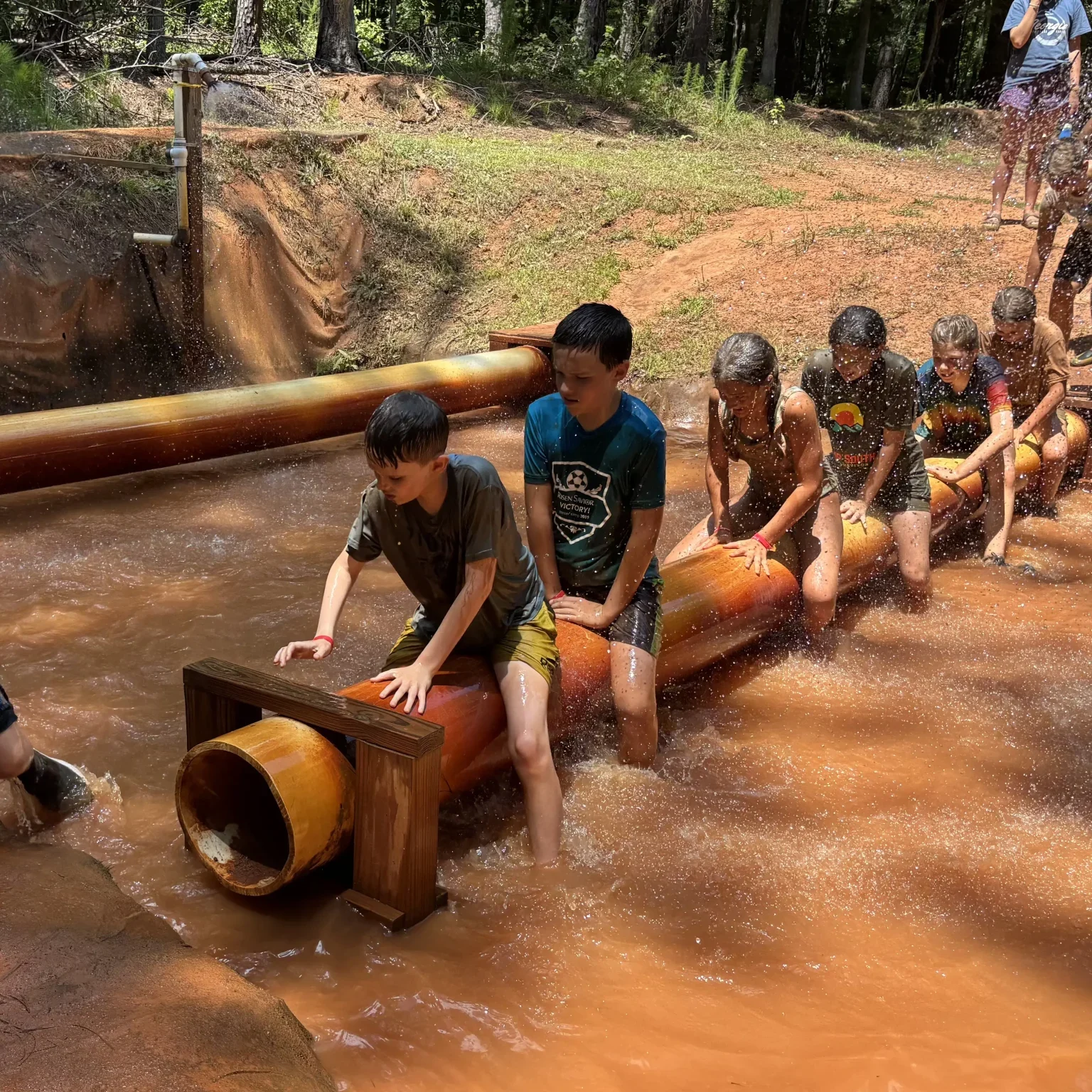 Children participating in an outdoor camp activity involving water and balance